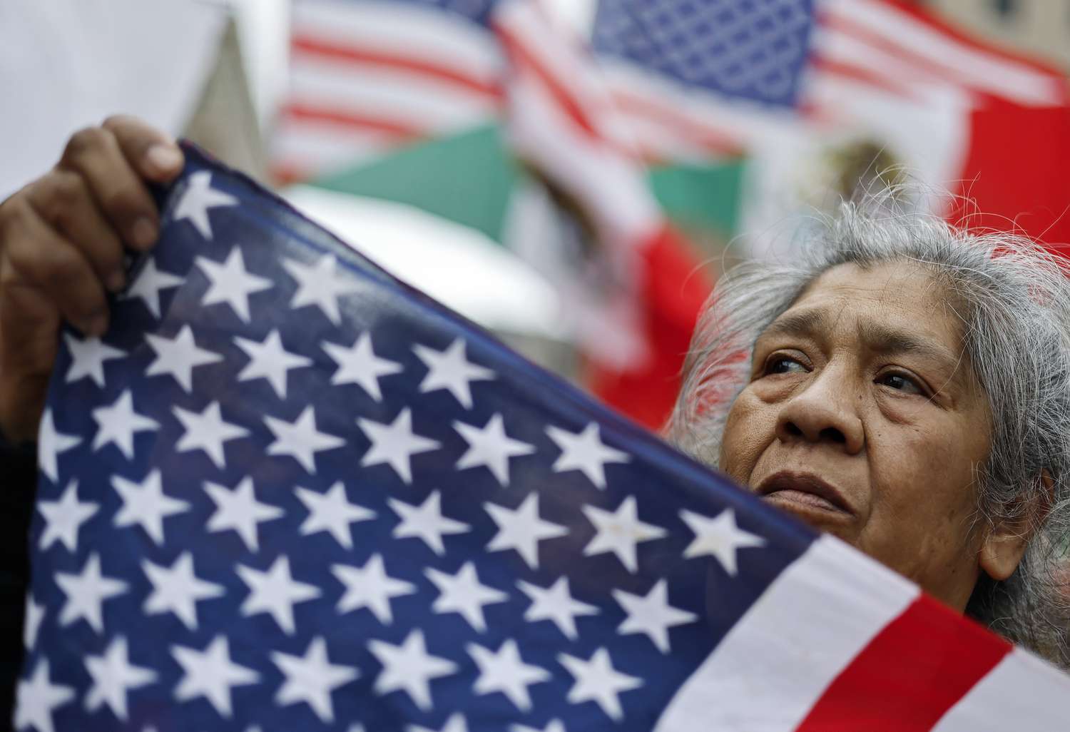 An immigrants rights supporter holds an American flag before marching downtown during a 'March for Dignity' on March 01, 2025 in Los Angeles, California.