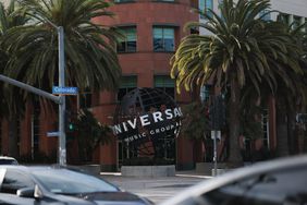 The Universal Music Group logo is seen on a statue of a globe outside a building, with trees on either side.