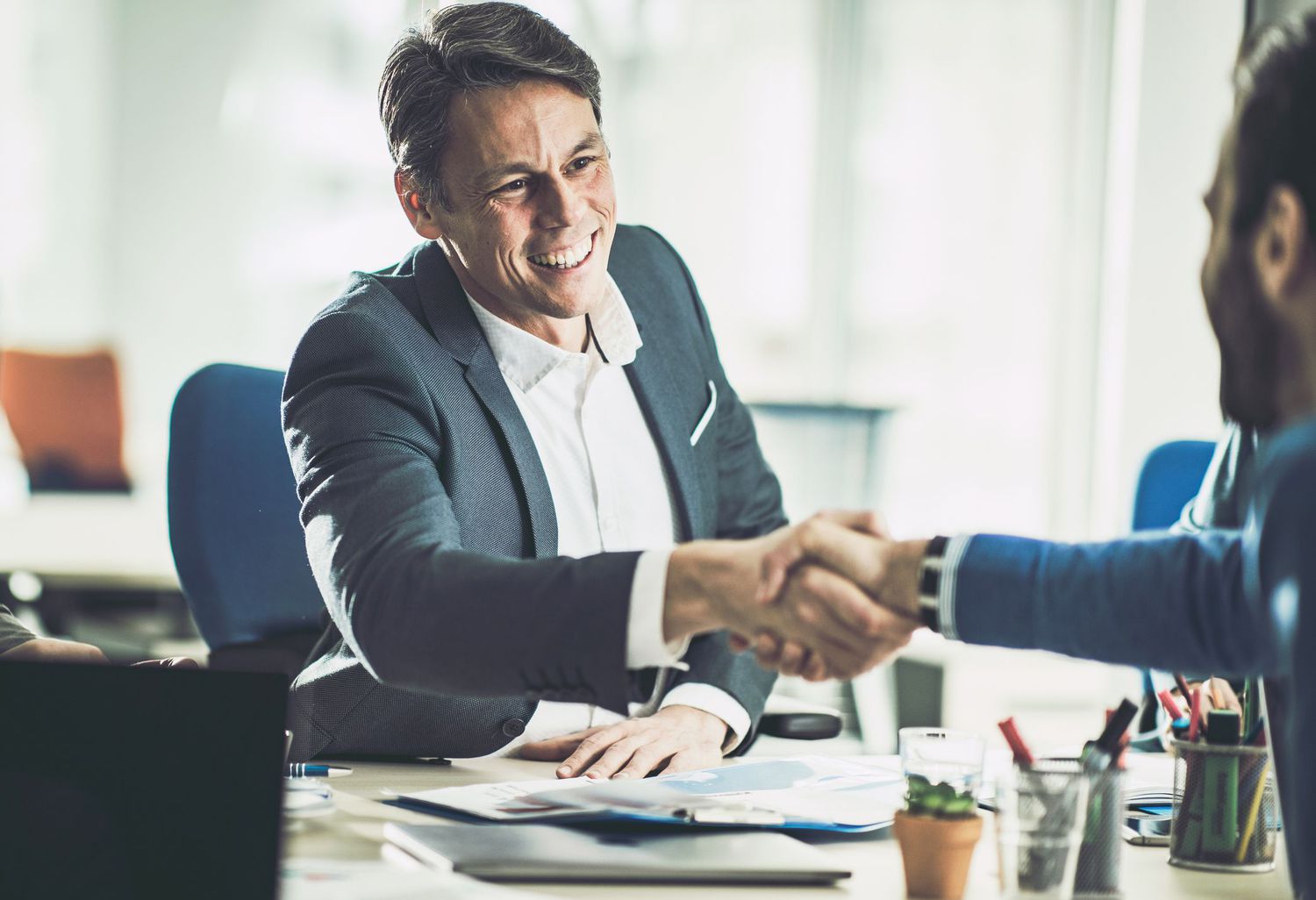 An agent shaking hands with his customer in his office.