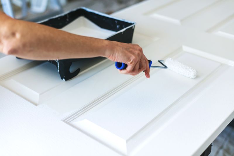 Mature Adult Female Painting Door White with Paint Roller