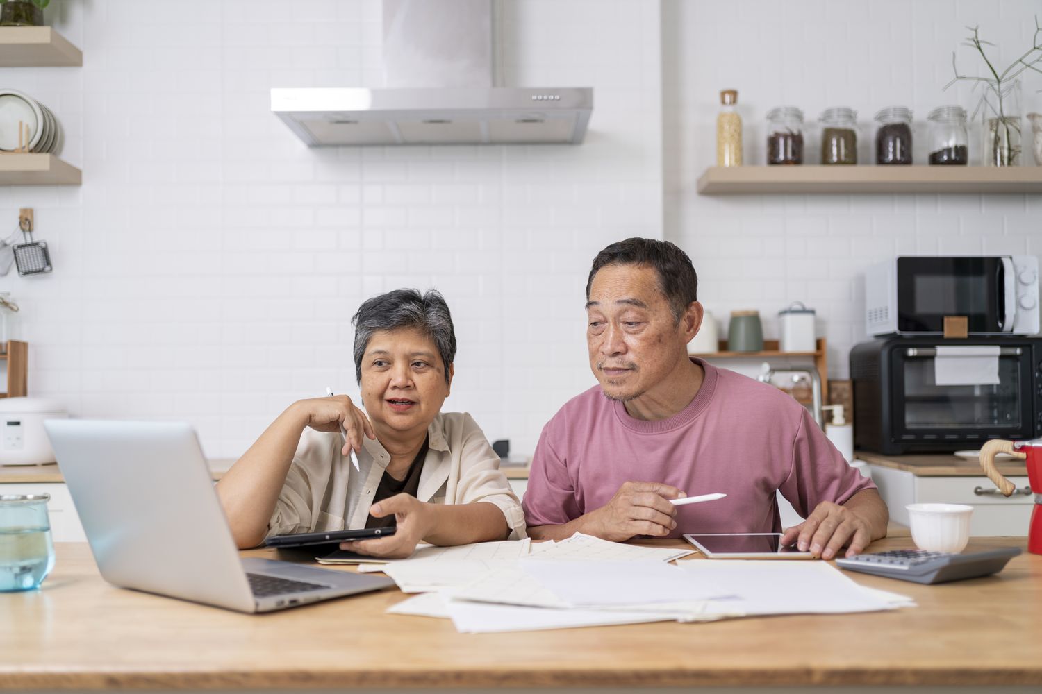 Happy Asian senior couple looking at their insurance options on laptop
