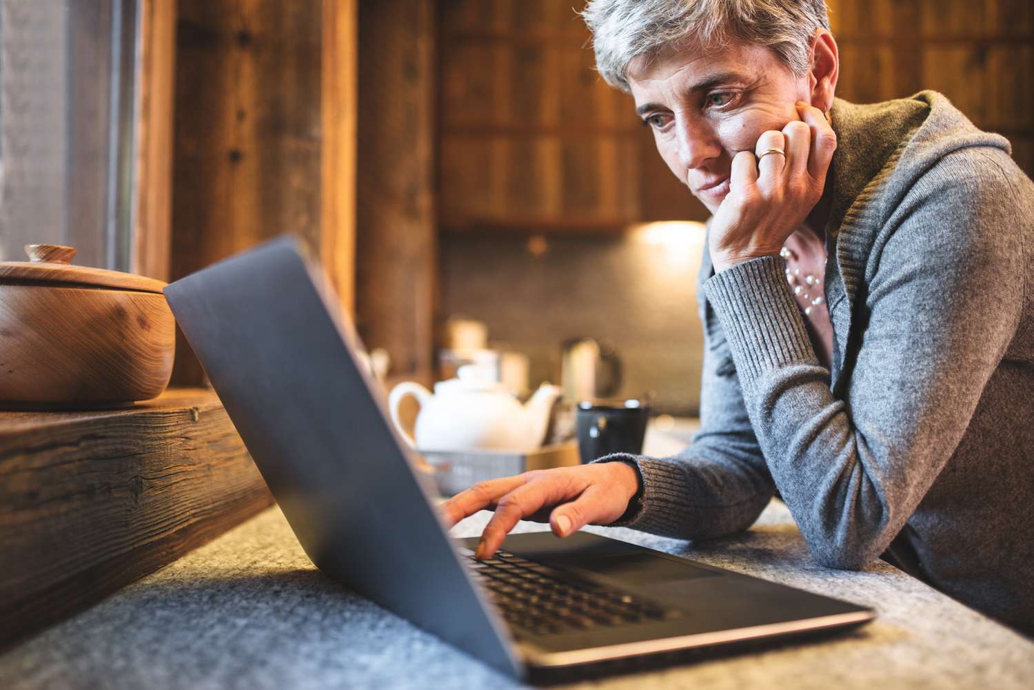 A mature person studies a laptop screen as they research Medicare Part B eligibility and costs.
