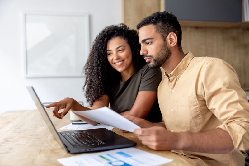 Young couple sitting at a table at home and looking at mortgage documents and online mortgage rates