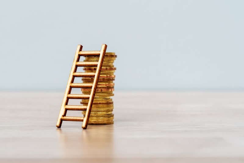miniature gold ladder on a stack of coins
