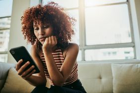 Woman sitting on couch looking at smartphone