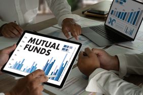 Tablets chowing mutual funds letters, three sets of hands around a table. 
