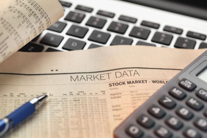 A page of market data on a laptop with calculator