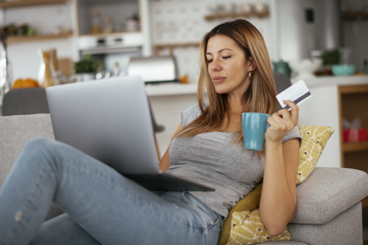 Woman making online purchase with credit card and a cup in her hand