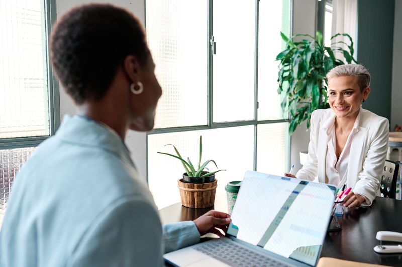 Black woman working next to a white woman at a laptop