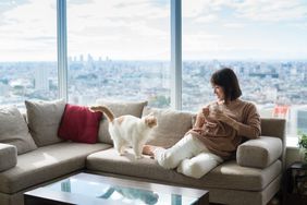 Woman on a couch with a cat holding a coffee cup in a high rise condo