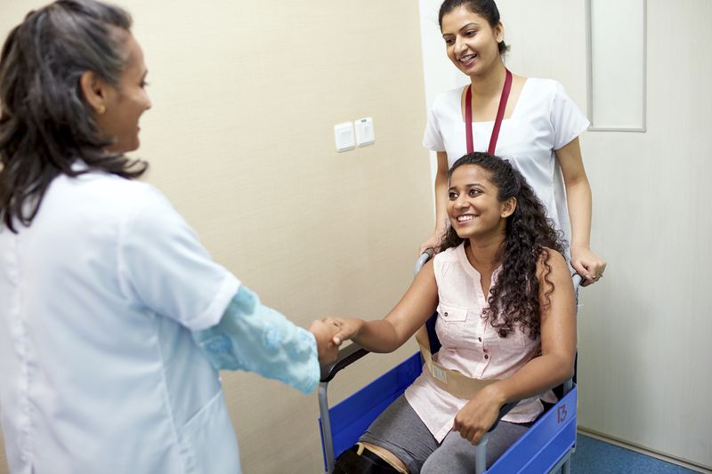 Female doctor greeting a girl in wheelchair