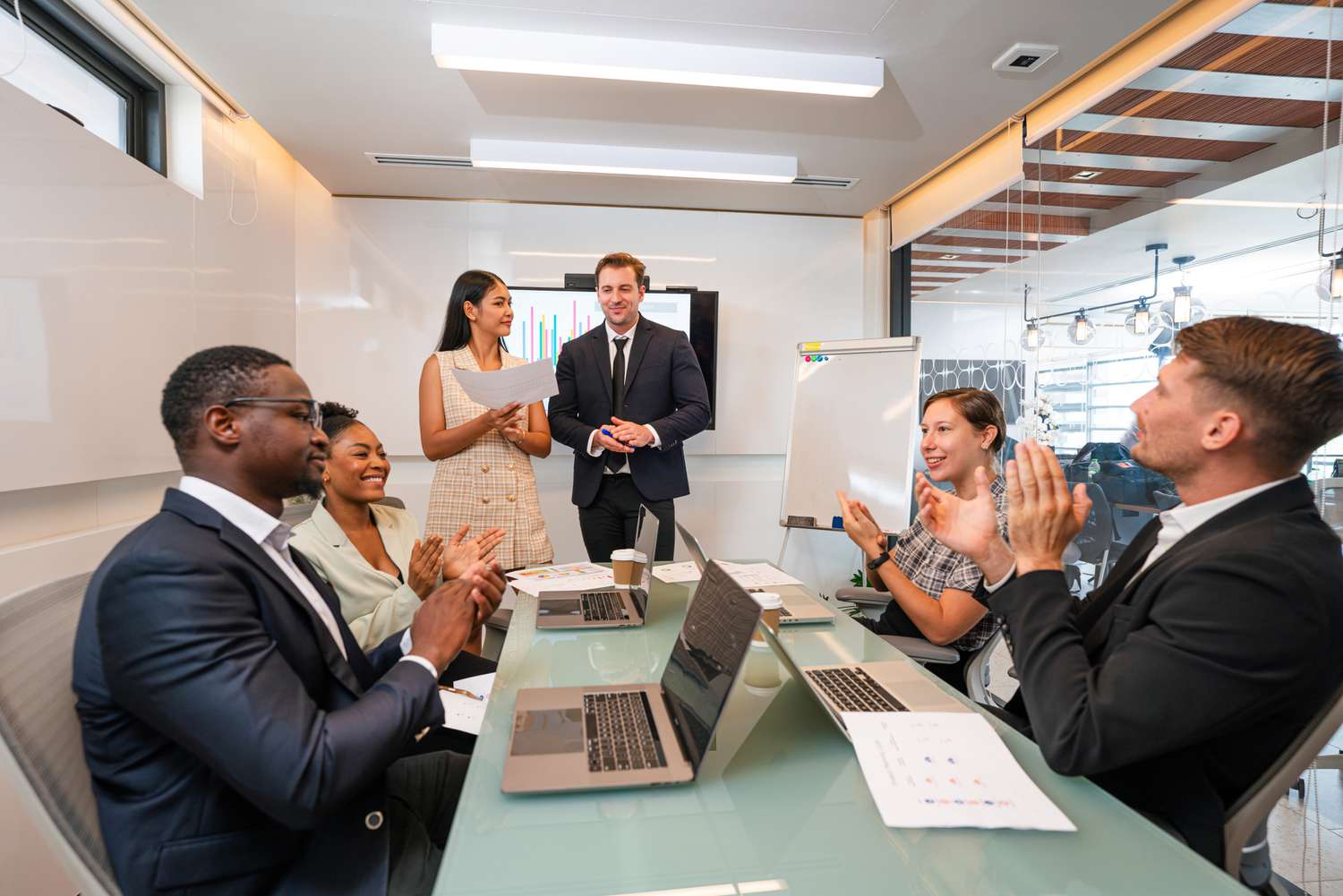Corporate members clapping in a meeting celebrating an upcoming spinoff announcement.