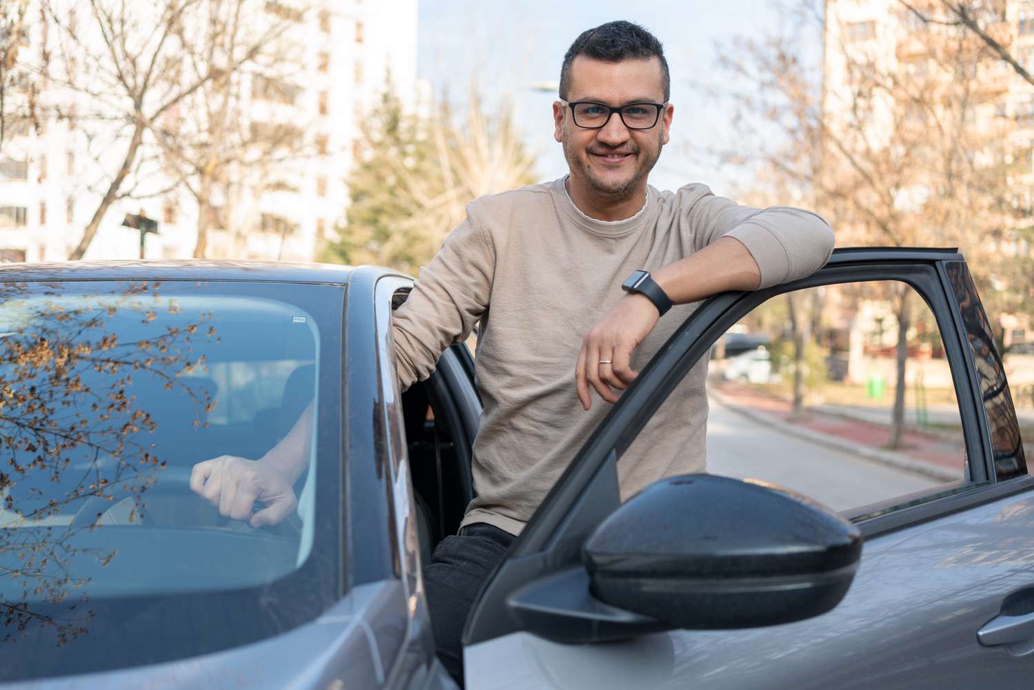 A man leans on his open car door.
