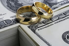 Wedding rings sit on a stack of cash.