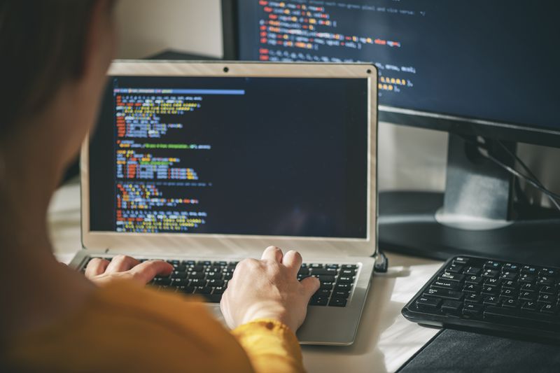 A close of a woman working on a program on a laptop at her home office.