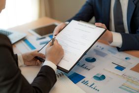 entrepreneur and his business partner signing important business insurance in office