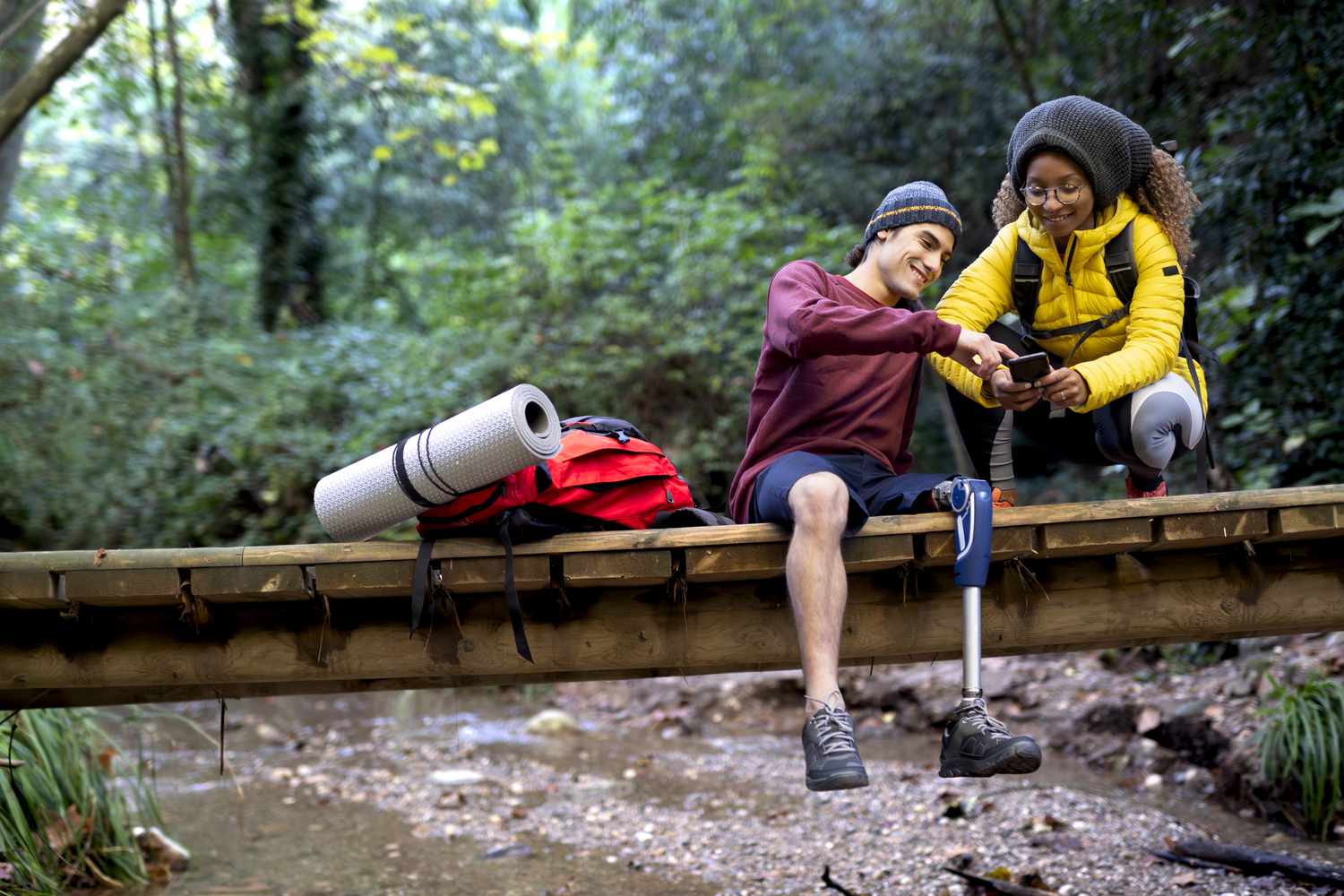 Man using a leg prosthesis with his girlfriend or friend spending a magnificent autumn day in the forest trekking or walking.