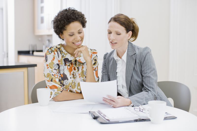 Businesswoman reviewing paperwork with woman.