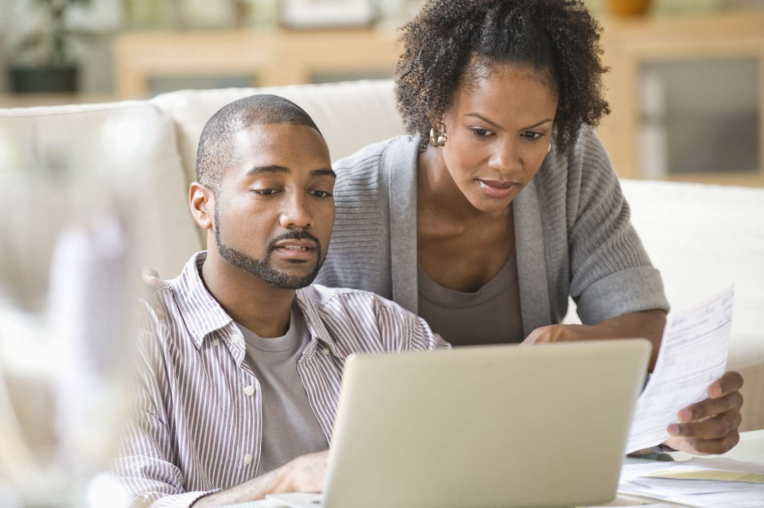 A man and a woman look at paperwork and a laptop