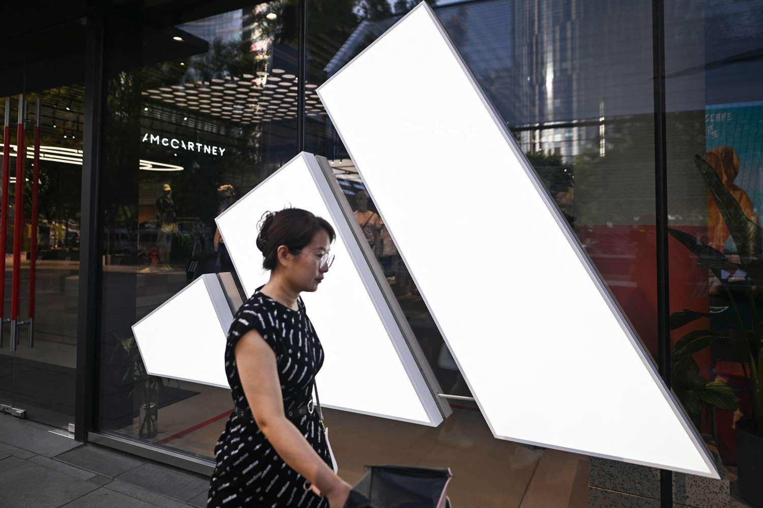 A woman walks past an Adidas store at a mall in Beijing on June 16, 2024