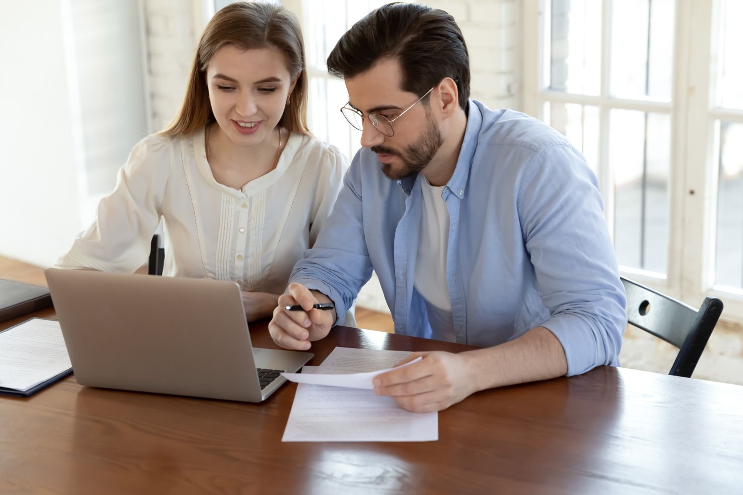 Young couple sitting in their dining room and looking together at online mortgage rates.