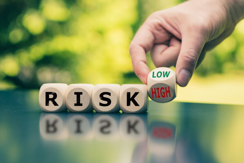 Cubes form the word risk with a hand turning cube from high to low risk.