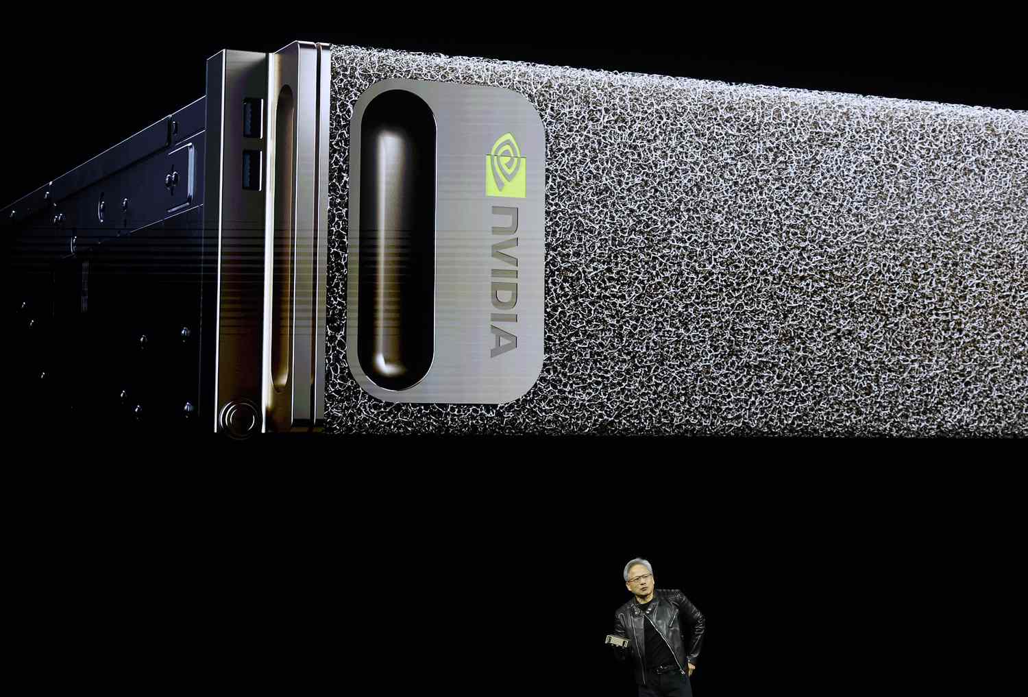 An Nvidia computer is displayed on a screen behind CEO Jensen Huang.
