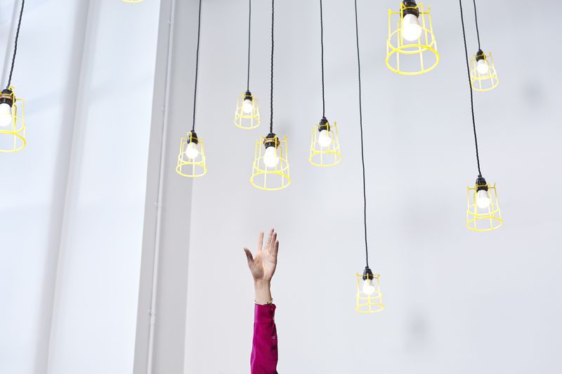 A hand reaching for conceptual idea lightbulbs