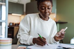 A woman holding cash and doing a budget