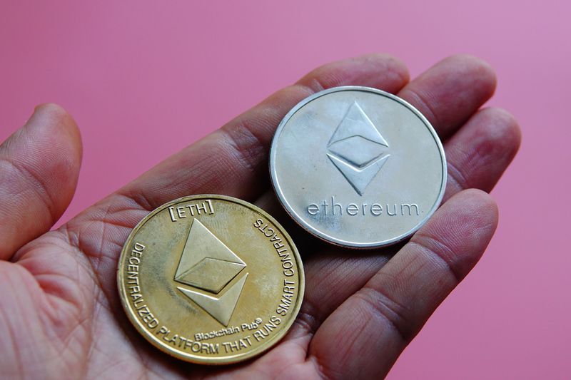 An investor holds in their hand two mock tokens of the blockchain-based Ethereum cryptocurrencies.