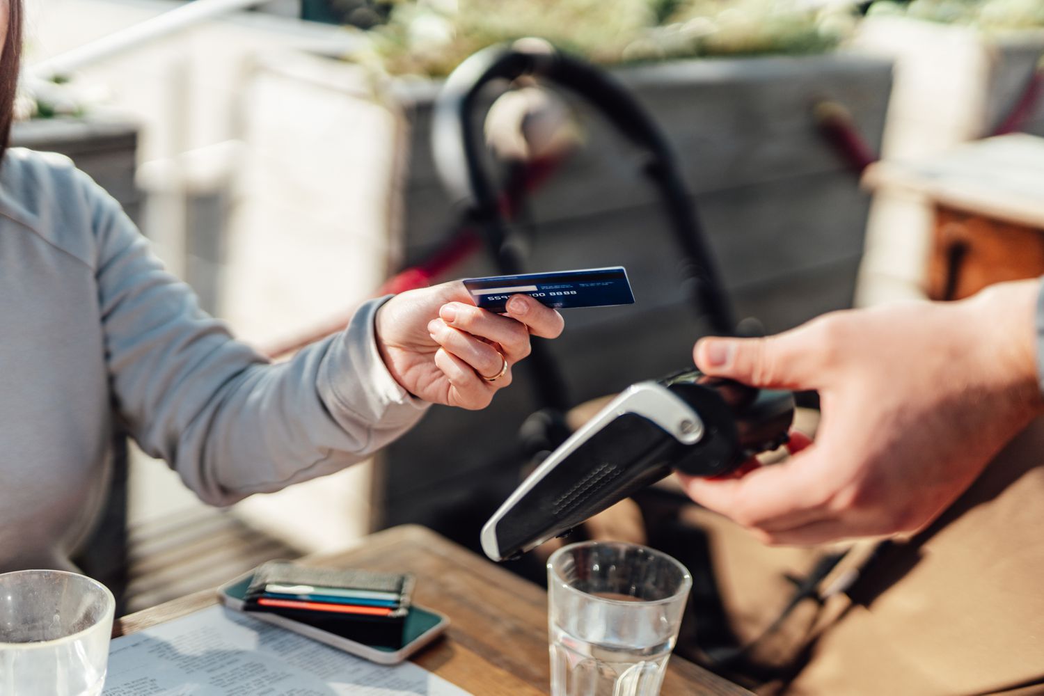 Close-up shot of a female hand using her credit card to scan and pay for a bill .