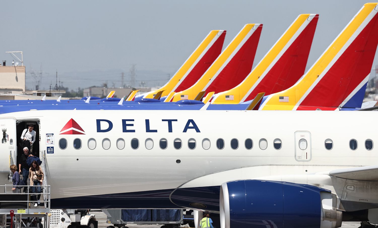 A Delta plane is seen in front of a row of Southwest Airlines planes, with their red and yellow tails visible.