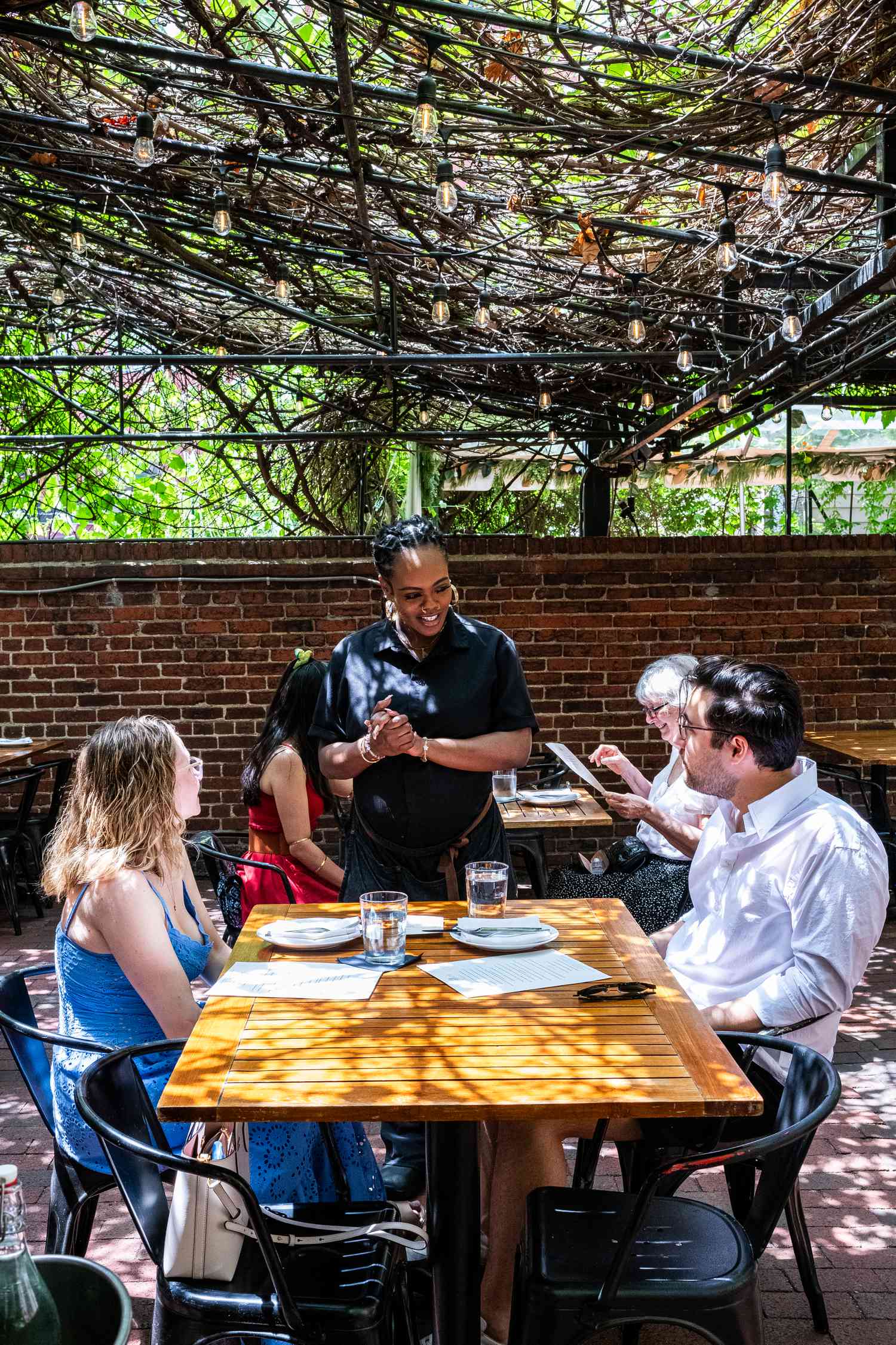 Waitress Amber Keys talks with Ella Lane and Justin Becker Gold at Iron Gate in Washington, DC on May 3, 2025.