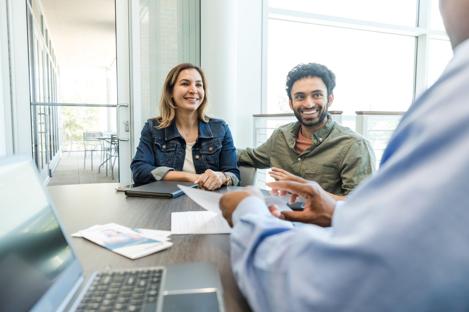 A smiling comple listen to a banker discuss their IRA.