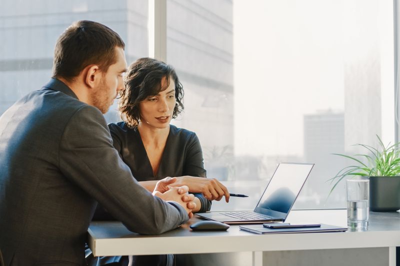 Two colleagues review information on a computer.