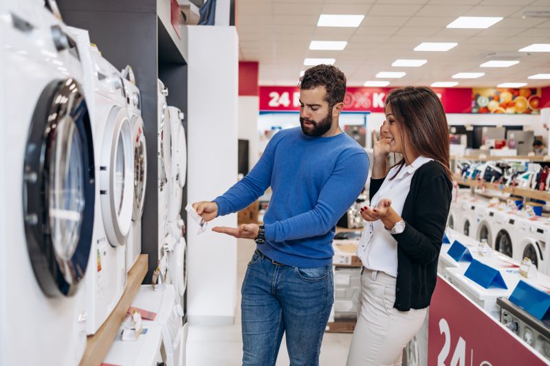 Young couple shopping for washing machine in appliance store
