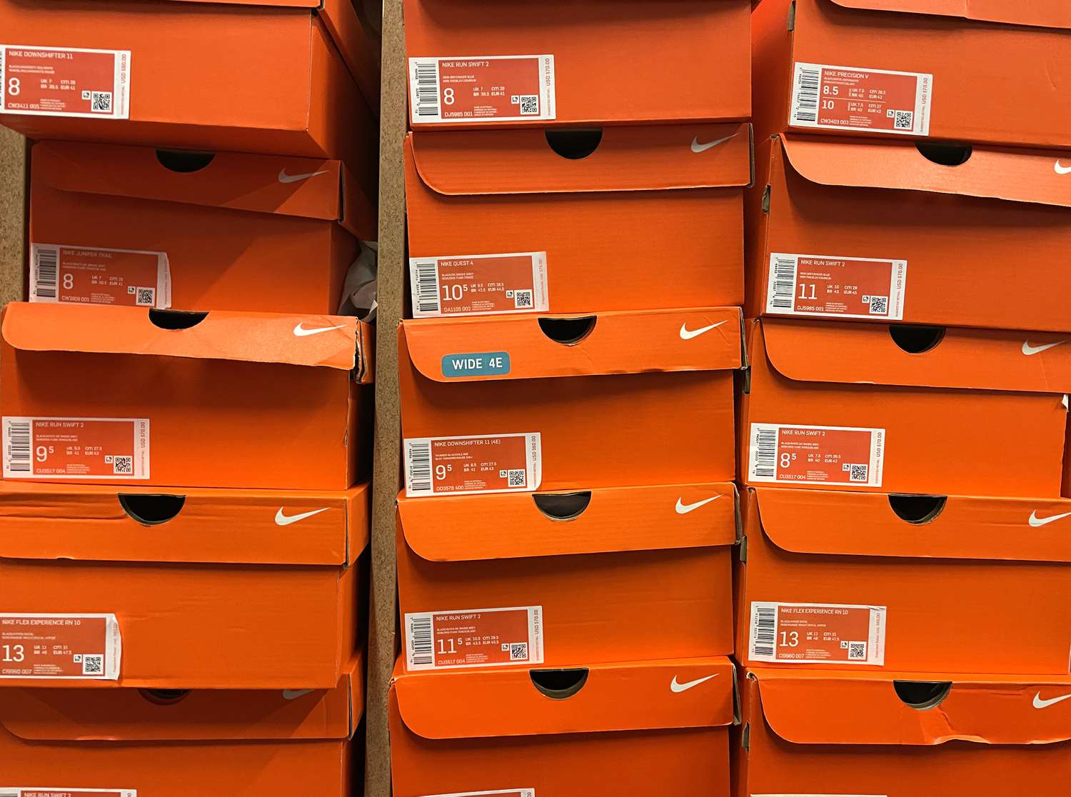 Stacks of Nike shoe boxes sit on a shelf at a shoe store.