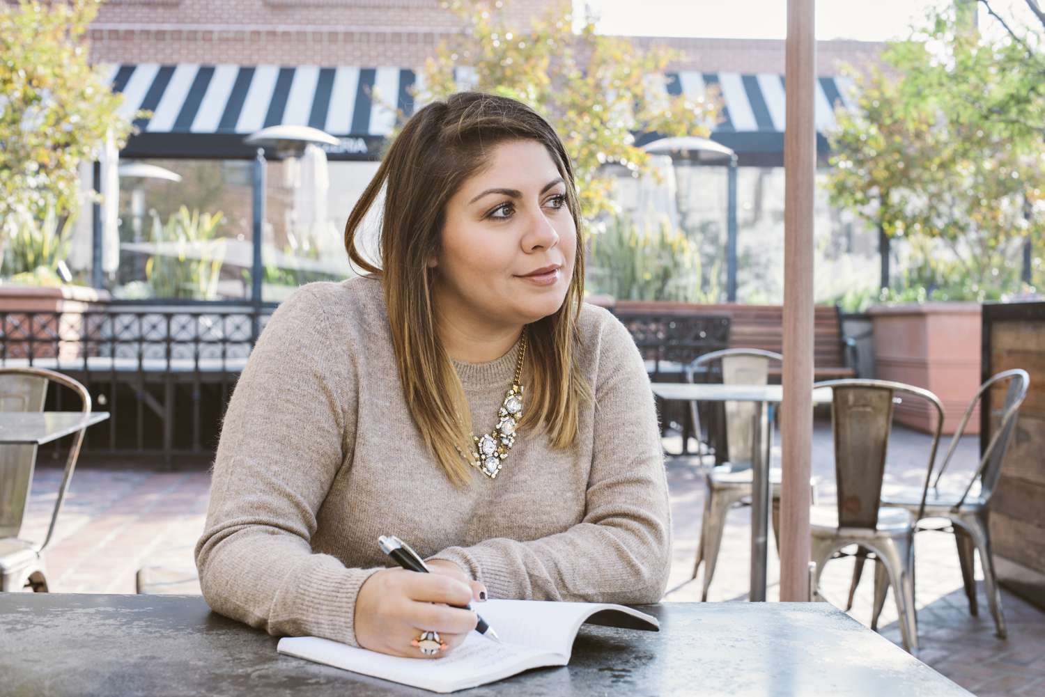 Woman sitting at an outdoor cafe writing in a notebook