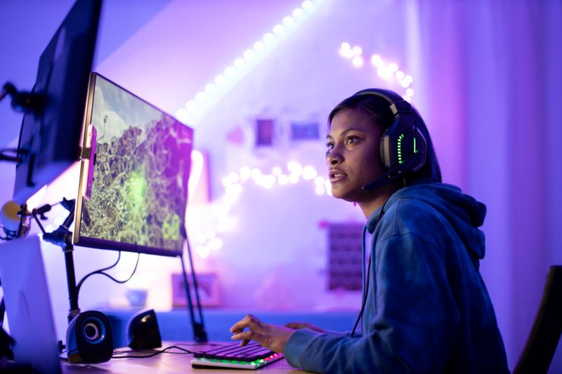 Person playing a three-dimensional computer game called Second Life using headphones and multiple monitors.