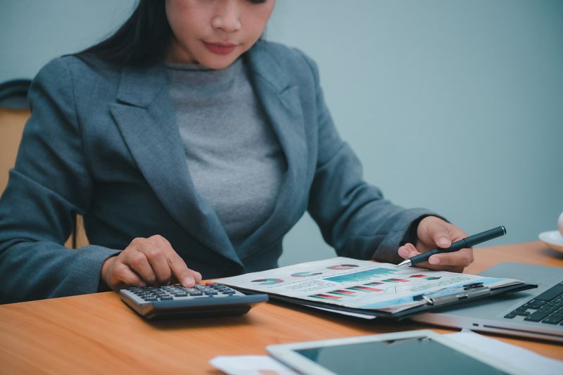 An accountant uses a calculator as they review documents showing the current portfolio holdings for an exchange traded fund.