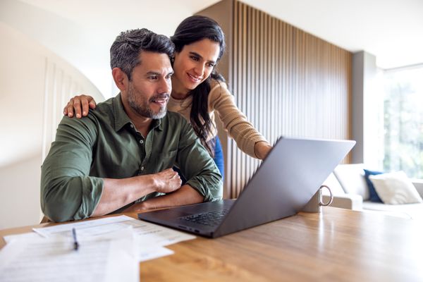 Two people looking at a laptop together while seated at a desk
