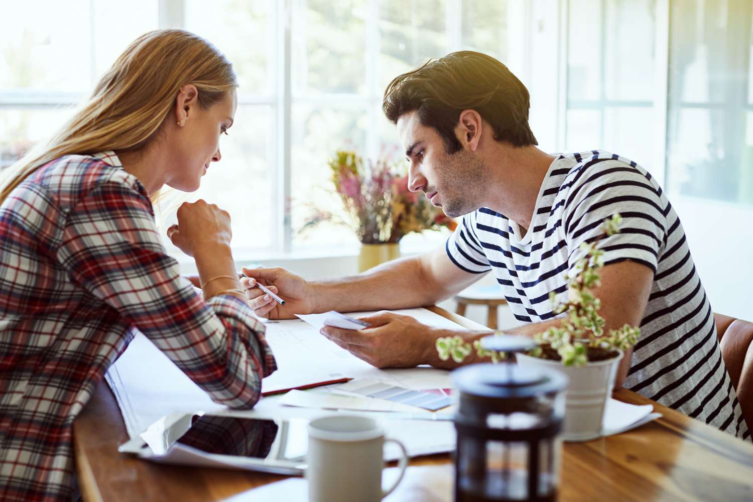 A young woman and a young man review documents together in a brightly light kitchen.