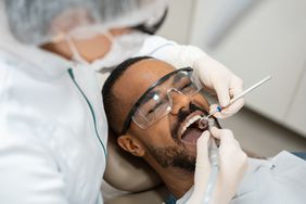 A dentist examines a young man's teeth in her office