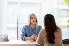 Businesswoman listens with a serious look on her face to a female client