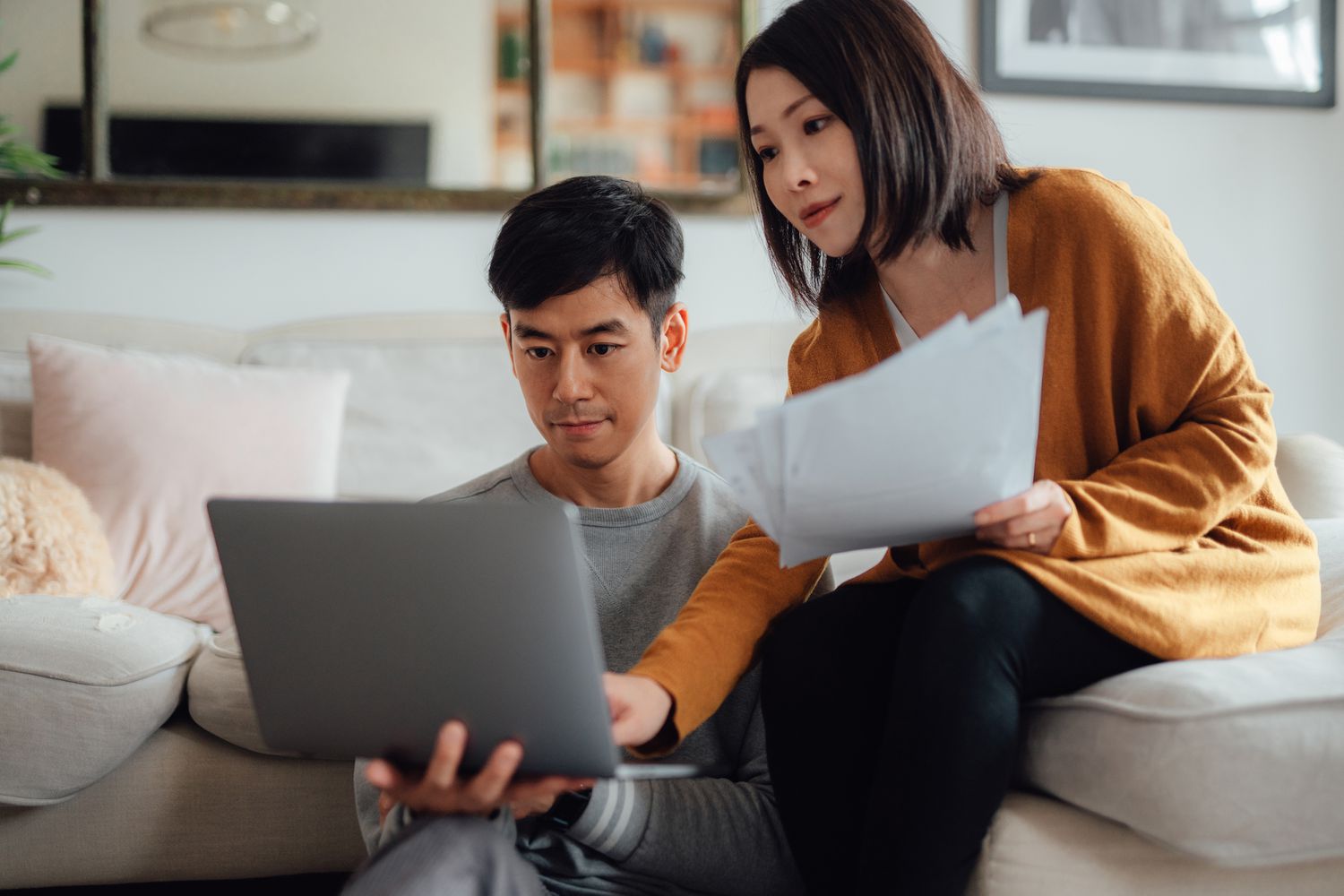 Young couple discussing savings accounts while using laptop