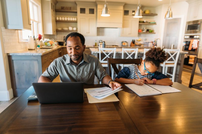 Dad and daughter doing work at the kitchen counter.