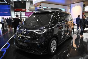 A Volkswagen autonomous concept van displayed at an exhibition with people in the background