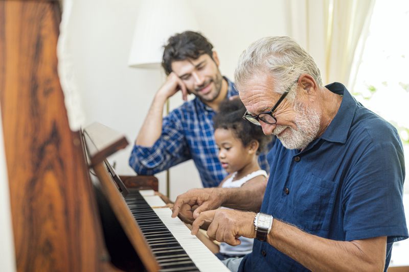 Three generations of a retiree's family gather around the piano for a quiet evening at home. 