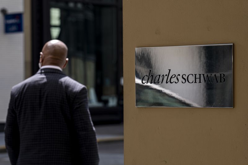 a man with his back to camera standing outside a Schwab brokerage firm.