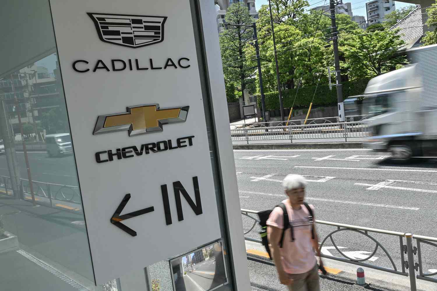 A pedestrian walks past a car dealership which sells US auto brands Cadillac and Chevrolet, along a street in Tokyo
